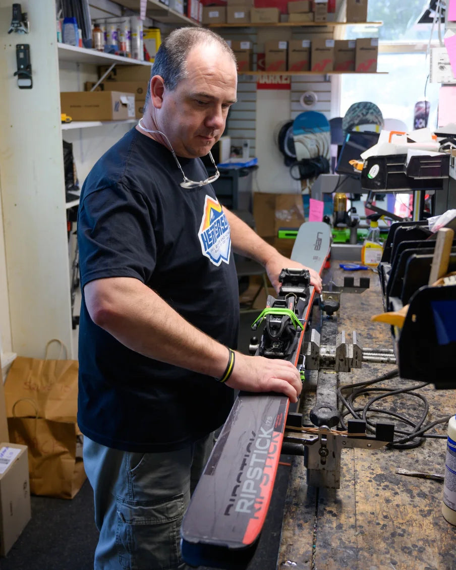 Ski technician preparing an Elan Ripstick at a workbench