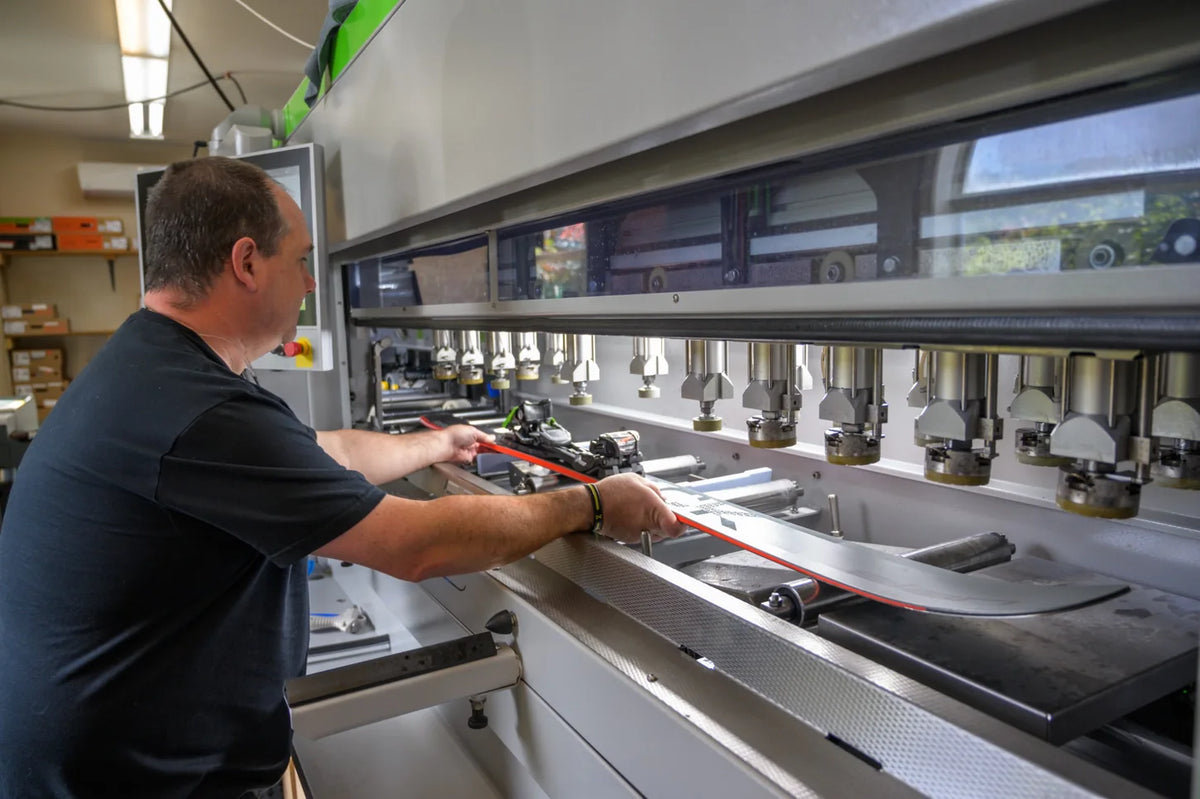 Ski technician feeding a ski into a machine