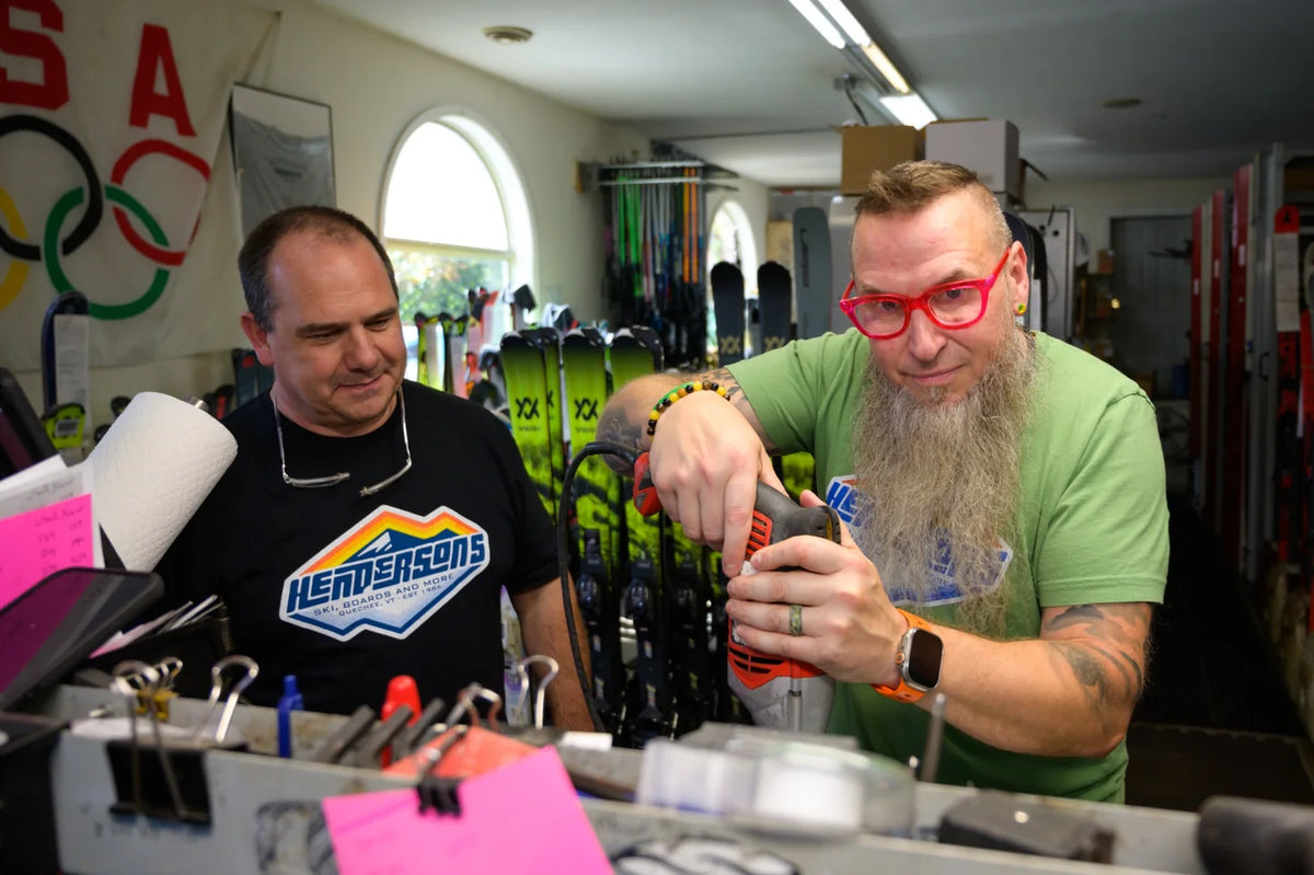 Two ski shop technicians working at a bench